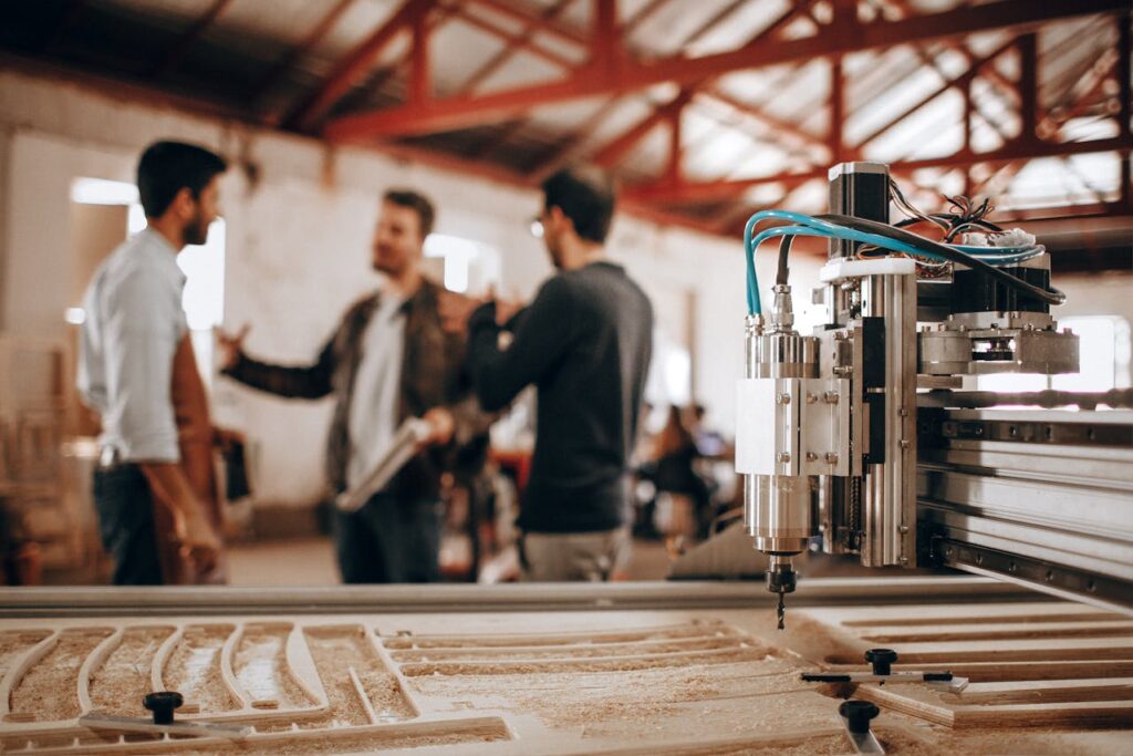 Engineers discussing manufacturing troubleshooting next to CNC machine